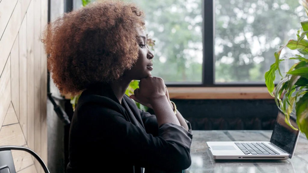 A women sat at a desk looking pensive